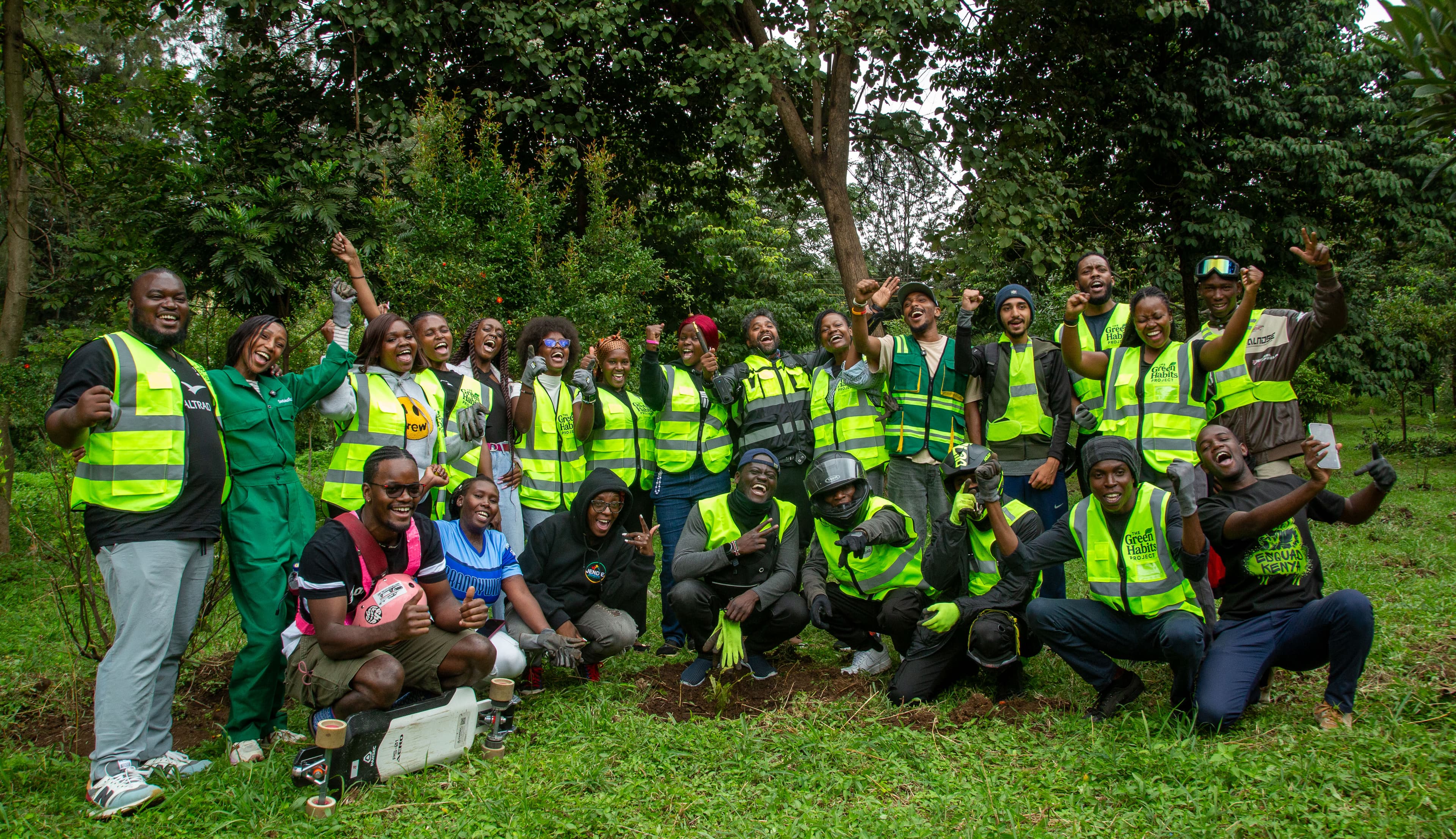 Green Habits community action group photo. The team poses together in a lush, forested environment in Nairobi, Kenya, celebrating tree-planting and restoration success.